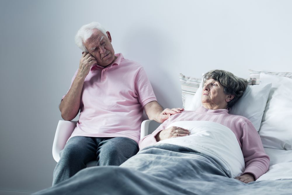 husband supporting elderly wife in bed